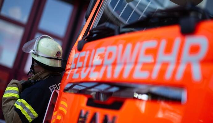 Feuerwehrmann steht neben einem Feuerwehrauto (Symbolbild) Feuerwehrmann steht neben einem Feuerwehrauto (Symbolbild)