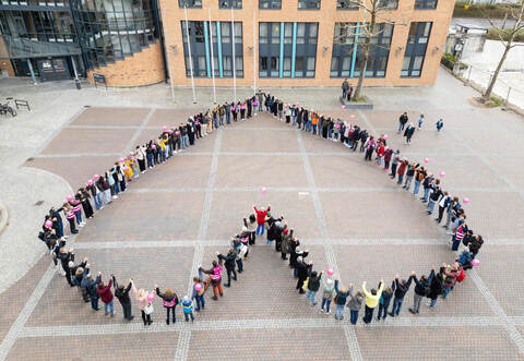 150 Menschen haben sich zu einem Herzen aufgestellt.