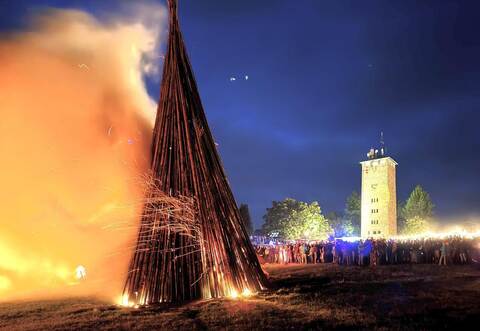 Zahlreiche Besucher verfolgen das Entzünden des Holzstoßes.