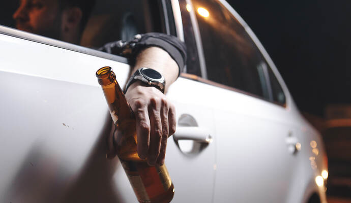 Ein mutmaßlich betrunkener VW-Fahrer fuhr am Sonntagmittag eine Frau in Dobel an und flüchtete danach von der Unfallstelle. (Symbolbild) Drunk young man drives a car with a bottle of beer. This is a campaign picture of Don't Drink for Drive.