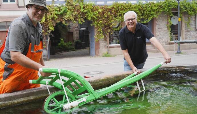 Harry Faaß (links) vom Bauhof und Vereinssprecher Gerold Benz von den Steiner Vogelfreunden legen den Schaltkarch zum Wässern in den Dorfbrunnen.