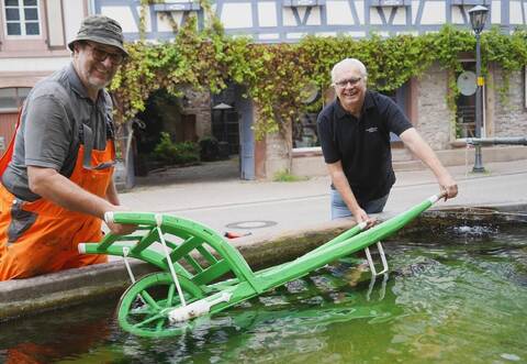 Harry Faaß (links) vom Bauhof und Vereinssprecher Gerold Benz von den Steiner Vogelfreunden legen den Schaltkarch zum Wässern in den Dorfbrunnen.