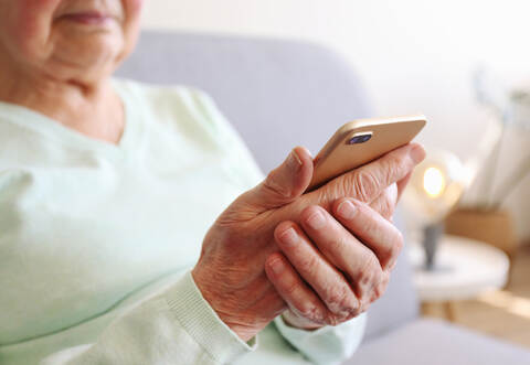 Elderly woman holding blank screen cell phone gadget in hands. Old lady with wrinkled skin trying to vigure out touchscreen smar
