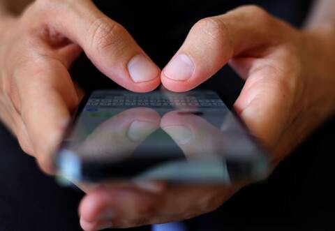 Ein Jugendlicher tippt auf einem Smartphone eine Nachricht.