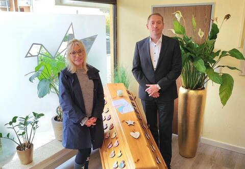 Maria Weller und Nick Köhler, Geschäftsführer des Pforzheimer Bestattungshauses, präsentieren einen mit von Kindergartenkinder verzierten Sarg.