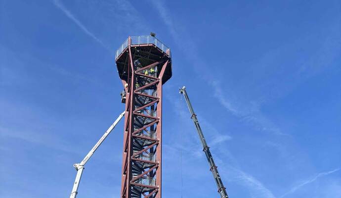 Das Dach der „Hohen Warte“ wurde bereits mit einem Kran angehoben. Jetzt ziehen Gerüstbauer eine Plattform hoch. Diese soll die Aussichtsfläche tragen, sodass schließend die Treppen aus dem Turm geschnitten werden können.