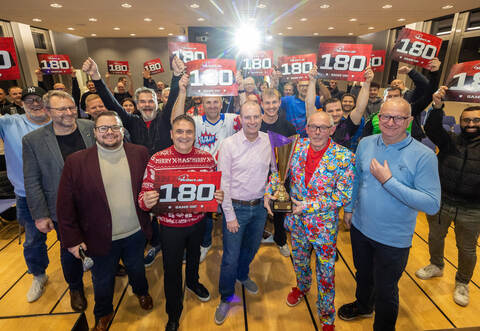 „180“, die mit drei Würfen erreichbare Höchstpunktzahl, schwebt über allen und allem:&nbsp;Im PZ-Forum kocht die Stimmung hoch mit Moderator Kevin Bregula am Mikro, links dahinter PZ-Chefreporter Alexander Heilemann, rechts neben Bregula Initiator Heiko Faber, Ronny Walter, Vorstand Raiffeisenbank Kieselbronn, Ralph Augenstein, Vorstand des 1. FC Kieselbronn, und Bernd Fritz, der sportliche Leiter (von links).