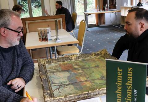 Ralf Recklies (links) präsentiert Aaron Gärtner vom Auktionshaus Bamberger das Ölgemälde eines unbekannten Malers. Hinten rechts: Charles Bamberger junior, der ebenfalls Kunstwerke geschätzt hat.