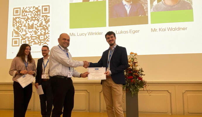 Ein Handschlag auf ausgezeichnete Arbeit im Bereich der Displaytechnologie: Lukas Eger und der amtierende Präsident der Society for Information Display (SID), Prof. Dr. John Kymissus von der Columbia University.