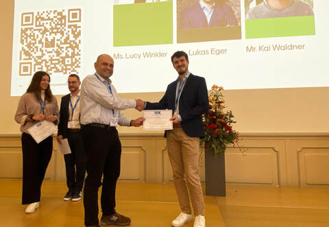 Ein Handschlag auf ausgezeichnete Arbeit im Bereich der Displaytechnologie: Lukas Eger und der amtierende Präsident der Society for Information Display (SID), Prof. Dr. John Kymissus von der Columbia University.