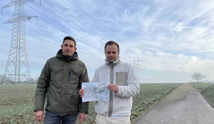 Verunsichert sind Anwohner wie Hendric Reeb (links) und Benjamin Georgopoulos im Gebiet „Kohlplatte“. Die Familienväter zeigen, dass über diesen Weg die Windkraftflächen bei Serres erschlossen werden sollen. Auf der Skizze sind die zu erwartenden Windradpositionen und Abstände zu den Häusern zu sehen.