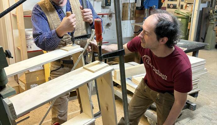 Patrick Streit (links) und Tobias Dobler arbeiten am neu angeschafften Leimständer, der für den Betrieb zur Massivholzbearbeitung essenziell ist. rose