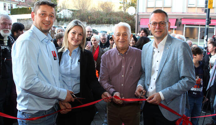 Das rote Band zur Neueröffnung von „Johann’s Imbiss“ durchschneiden in der Mühlacker Bahnhofstraße Ilias Margaritis (von links) und seine Frau Ifigeneia Chaktsi gemeinsam mit dem Imbiss-Gründer, Vater Johann Margaritis, und Oberbürgermeister Stephan Retter. Dahinter warten zahlreiche Kunden auf den Einlass.