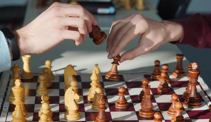 Dass an einem Brett zwei Hände gleichzeitig an eine Figur greifen, ist beim Schach eigentlich nicht vorgesehen. Doch für das Pressefoto haben die Schüler eine Ausnahme gemacht.