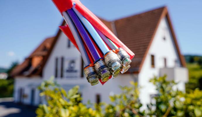 Bündel mit Umhüllungen für Glasfaserkabel vor einem Wohnhaus