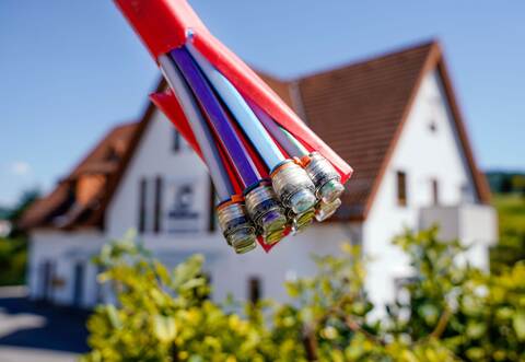 Bündel mit Umhüllungen für Glasfaserkabel vor einem Wohnhaus
