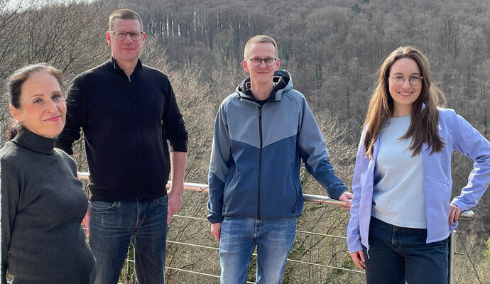 Die Anwohnerinnen der Siedlung Sonnenberg, Gisela Borrmann (links) und Carmen Borrmann (rechts), zeigen zusammen mit Carsten Buck-Tschonitsch (Zweiter von links) und Patrick Leicht von der BI „Vernunftenergie auf der Platte“ auf einem Balkon die gegenüberliegende Anhöhe, auf der zwei Windräder gebaut werden sollen.