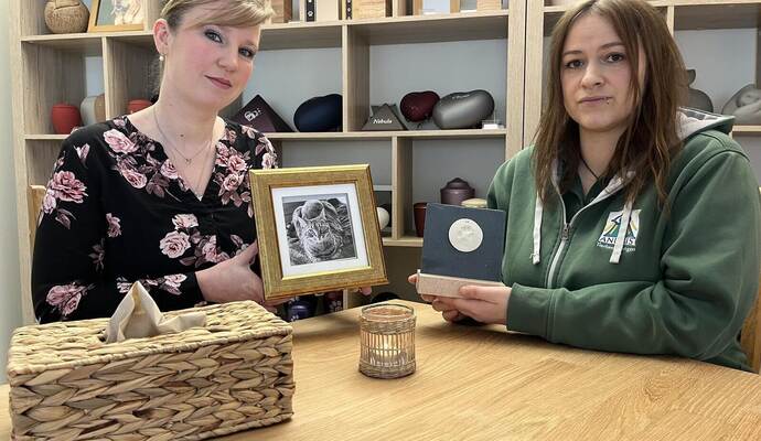 Jana Hinkelmann und Anubis-Filialbetreiberin Sandra Schmälzle (von links) mit der dezent gestalteten Urne für ihre Katze Happy, in der die Asche in der vertieften Rückwand des Bilderrahmens unauffällig Platz findet. Schmälzle hält einen Pfotenabdruck als Erinnerungsstück eines gestorbenen Tiers in der Hand .