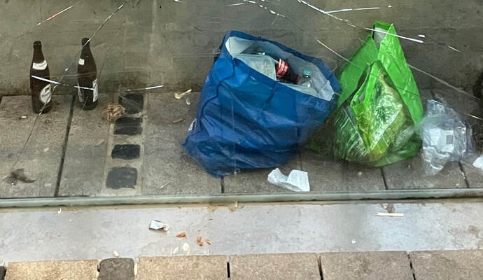 Bierflaschen hinter der Bank einer Bushaltestelle am Leopoldplatz in Pforzheim.