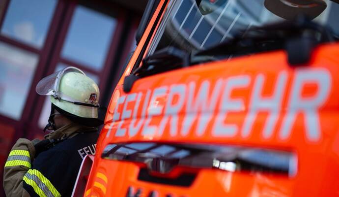 Feuerwehrmann steht neben einem Feuerwehrauto (Symbolbild)