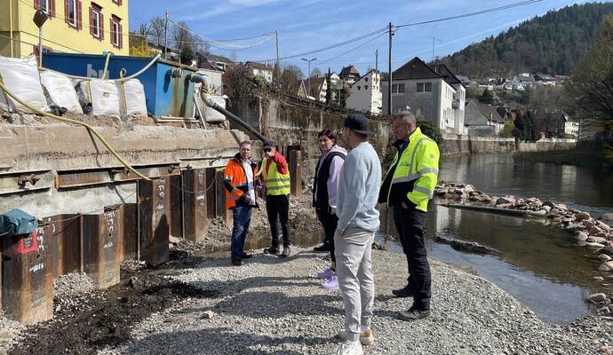 Bei der Baustellenbegehung entlang der Uferstützmauer an der Wildbader Straße erklärt Ingenieur Dirk Jelinek (links ) Anwohnern und Stadträten, was für Verzögerungen sorgte und wie es künftig weitergeht.