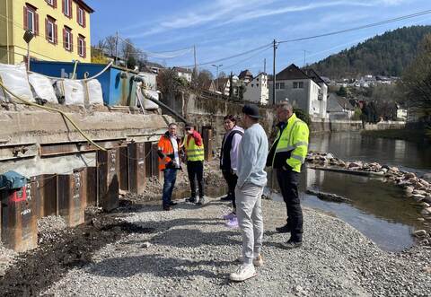 Bei der Baustellenbegehung entlang der Uferstützmauer an der Wildbader Straße erklärt Ingenieur Dirk Jelinek (links ) Anwohnern und Stadträten, was für Verzögerungen sorgte und wie es künftig weitergeht.