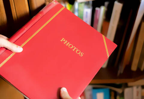 close up hand search and take the red photo album on the book shelf