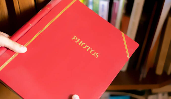 close up hand search and take the red photo album on the book shelf