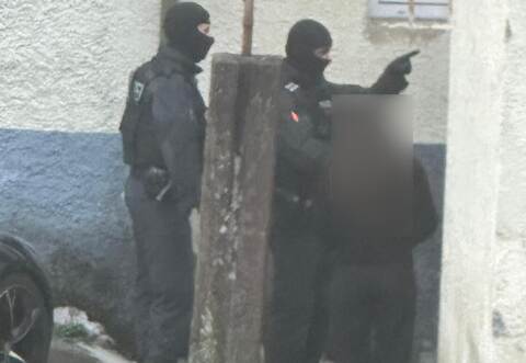 Anwohner beobachten im ersten Morgenlicht vermummte Polizisten an einem der durchsuchten Objekte.