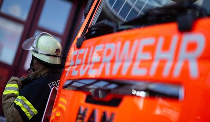 Feuerwehrmann steht neben einem Feuerwehrauto (Symbolbild)