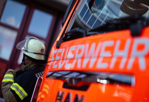 Feuerwehrmann steht neben einem Feuerwehrauto (Symbolbild)