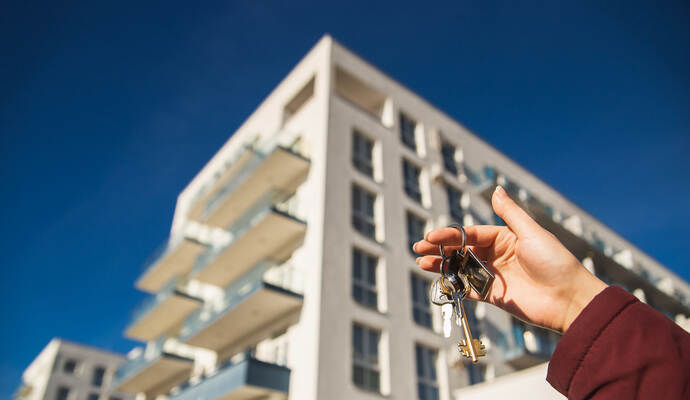 The concept of buying a new apartment. The woman hand holds the keys to a new apartment