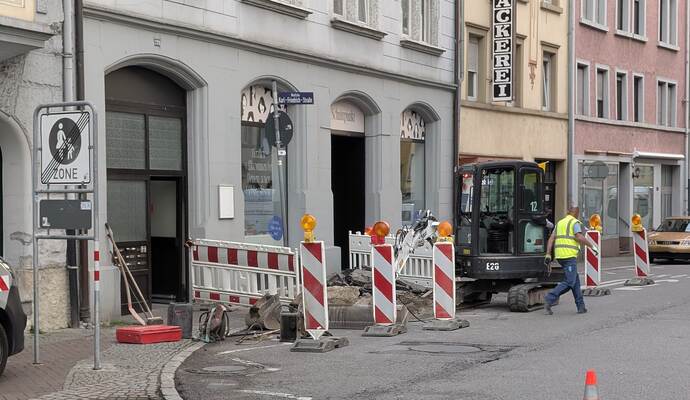 Mit einem kleinen Bagger legt der Mitarbeiter das Rohr in der Westlichen Karl-Friedrich-Straße frei.