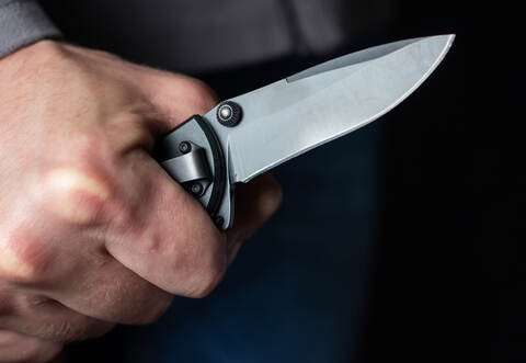 Man holding a knife in a threatening stance ready to fight