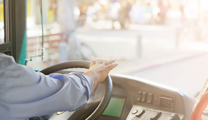 cropped shot of bus driver holding steering whee