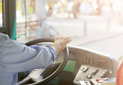 cropped shot of bus driver holding steering whee