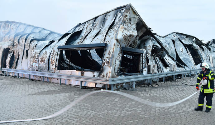 Ein Feuerwehrmann steht vor der Brandruine einer Fabrik für Lithium-Ionen-Akkus. Bei dem Feuer ist nach vorläufigen Angaben der Polizei ein Schaden in Millionenhöhe entstanden.