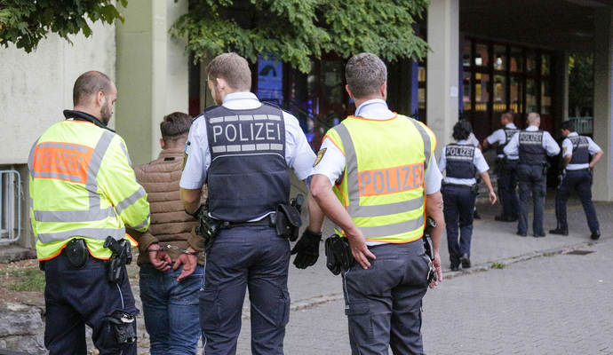 Die Einsatzkräfte führen einen Mann in Handschellen ab, der an der Auseinandersetzung beteiligt war.