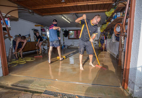 Raus mit der Brühe: Familie Diebold kämpft mit Helfern an der Dreisamstraße gegen die Überschwemmung. Vorne von links: Raphael Diebold und Michael Drapa.
