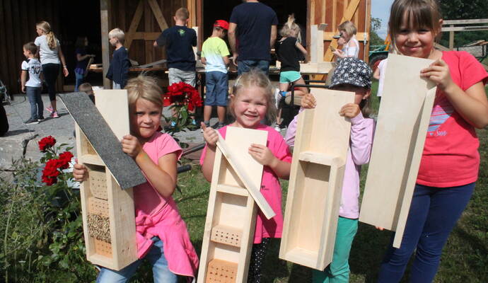 Vom bloßen Holz zum fertigen Haus: Während hinten an der Fronberg-Hütte gewerkelt wird, präsentieren Clara Zimmermann (von links), Lara Treiber, Nele Zendler und Anne Treiber die Fortschritte beim Bau der Insektenhotels.