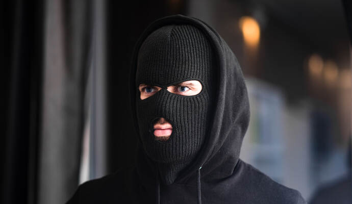 Auf dem Kopf trug der Mann eine Mütze, in welche Schlitze für Augen und Mund hineingeschnitten waren. Auf dem Kopf trug der Mann eine Mütze, in welche Schlitze für Augen und Mund hineingeschnitten waren.