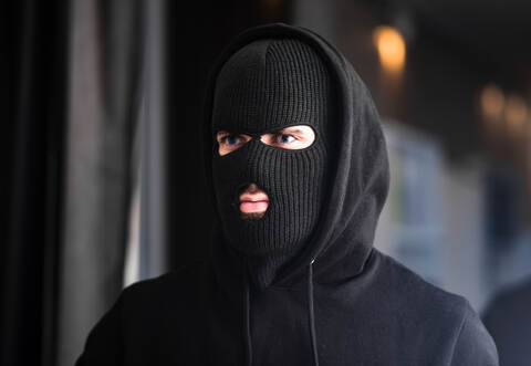 Auf dem Kopf trug der Mann eine Mütze, in welche Schlitze für Augen und Mund hineingeschnitten waren.