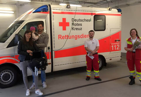 Eltern treffen Geburtshelfer: Ramona und Nico Bastian mit Tochter Emilia und dem schlafenden David in der Babyschale zusammen mit den DRK-Einsatzkräften Alexander Nießl und Hanna Grönheim.