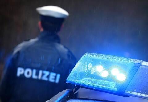 Ein Polizist vor einem Streifenwagen mit aktiviertem Blaulicht. Foto: Karl-Josef Hildenbrand/dpa