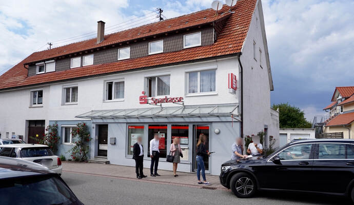 Mitarbeiter der Bank stehen gemeinsam nach dem Überfall mit der Polizei vor der Filiale. Nach Auskunft der Polizei wurde glücklicherweise niemand verletzt.