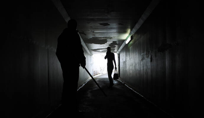 Man harassing a woman in a dark tunnel