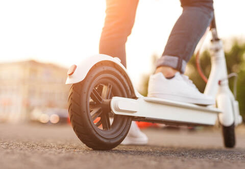 Crop man riding electric scooter