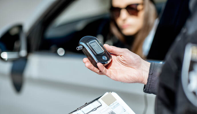 Bei der Unfallverursacherin wurde ein Alkoholwert von 1,6 Promille festgestellt. Policeman with alcotest device