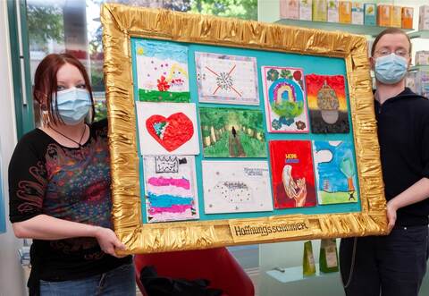 Anastassia Biederstaedt hängt mit ihrem Mann Christian Biederstaedt in der Herz-Apotheke Mühlacker das Bild "Hoffnungsschimmer" auf.