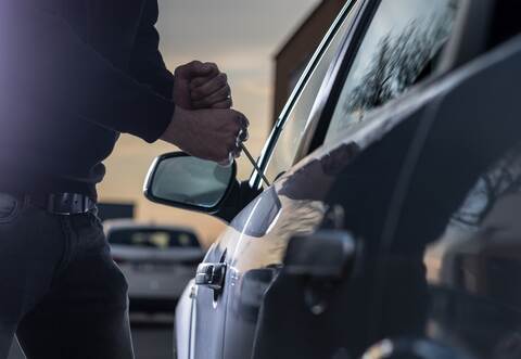 Auto thief in black balaclava trying to break into car